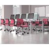 A row of pink swivel chairs in front of a white desk with screens on