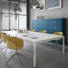 A wall of blue lockers behind a large white table with yellow chairs