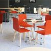 Cafe setting with red chairs around a circular wooden table