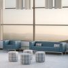 Blue grey armchair and sofa sitting behind four cylindrical stools