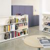 White bookcases filled with books, magazines and newspapers, in an office or reception setting with a coffee table and storage cabinets